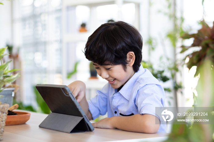 child looked excited and looked at the tablet while studying electronics at home.