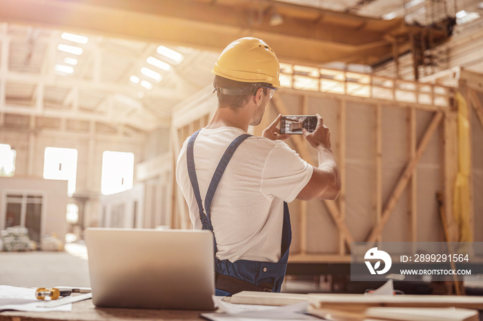 Male worker taking building photo with mobile phone