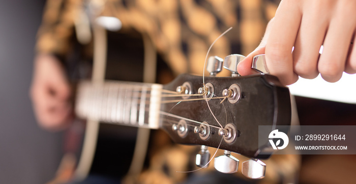 The young man tuning the electric guitar.