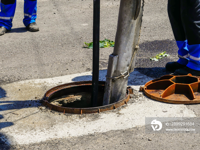 Workers cleaning the sewage at a residentual house on a bright sunny day.