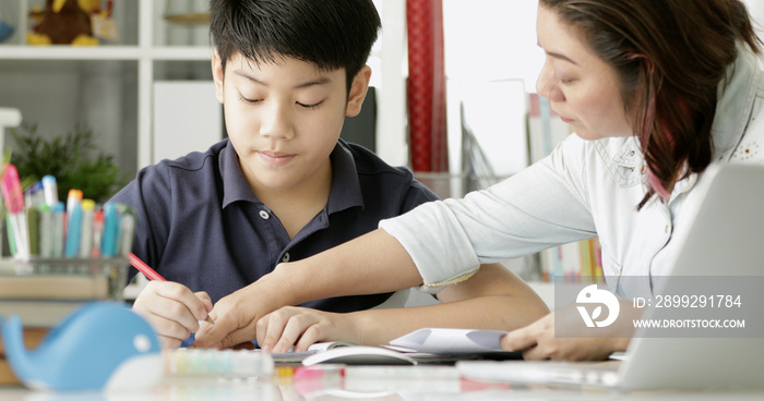 Cute asian mother helping your son doing your homework .