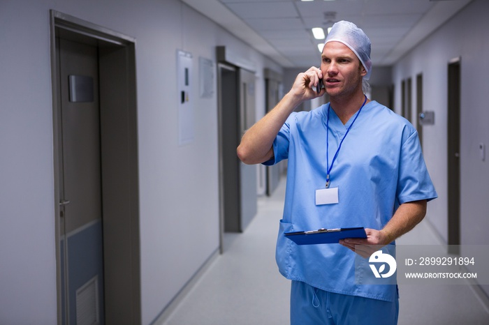 Surgeon standing in corridor and talking on mobile phone