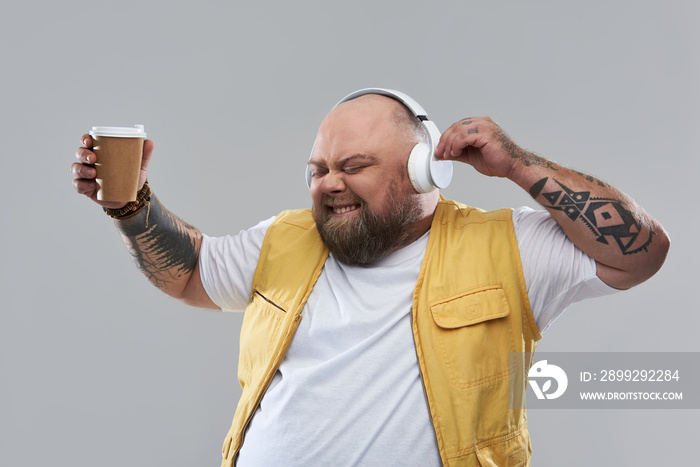 Waist up of emotional man dancing with cup of coffee