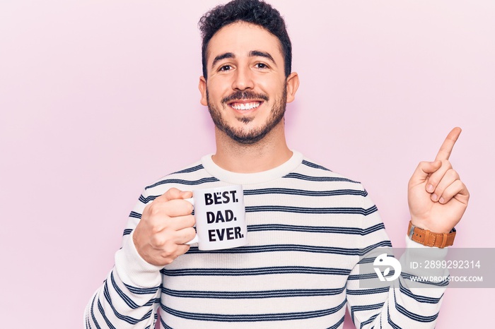 Young hispanic man drinking mug of coffe with best dad ever message smiling happy pointing with hand and finger to the side