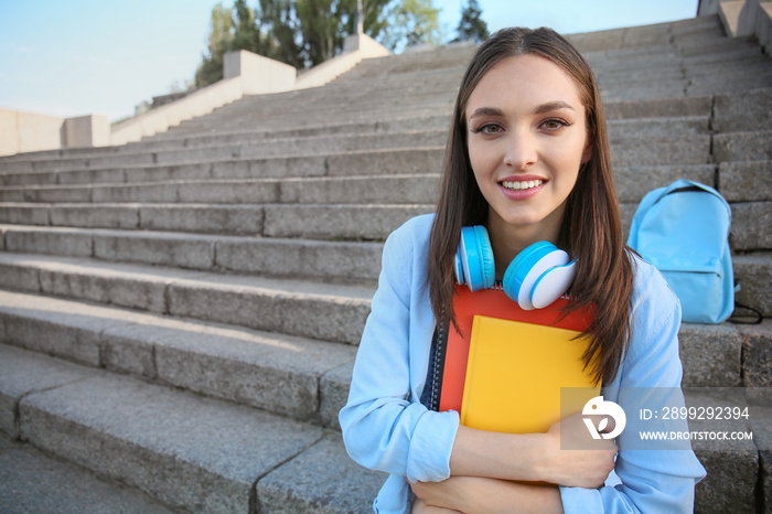 Beautiful female student sitting on stairs outdoors