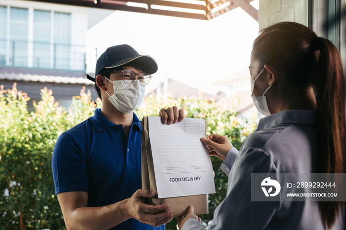 Delivery of an asian man handing a bag of food to a female customer at the door while wearing a protective mask during a virus epidemic.