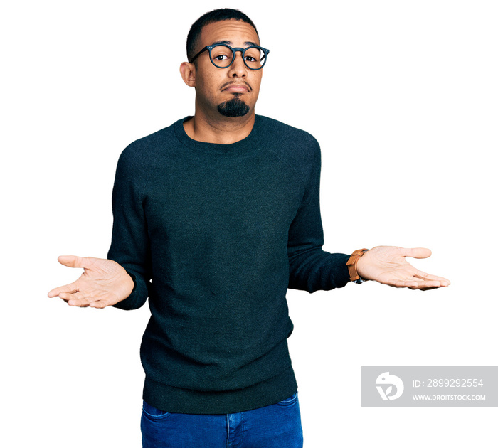 Young african american man wearing casual clothes and glasses clueless and confused expression with arms and hands raised. doubt concept.