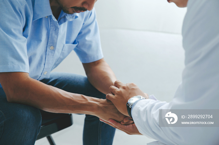 Male doctor’s hands holding male patient’s hand for encouragement and empathy. reassuring and support. Patient cheering and support