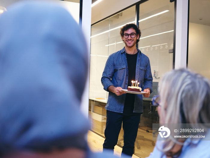 UK, London, Smiling man with birthday cake entering conference room