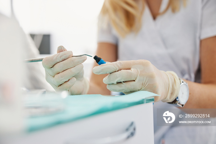 Woman reaching inside composite material bottle with dental carver