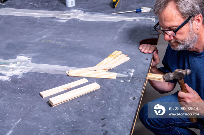 Worker adds shims leveling new pool table slate