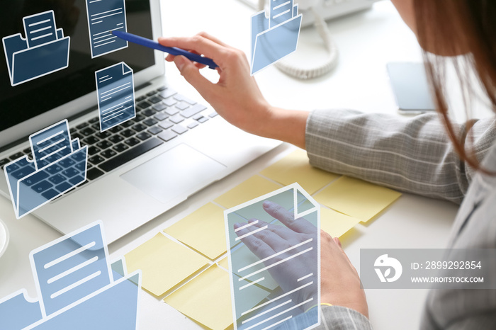 Young businesswoman with sticky note papers, laptop and digital files at her workplace