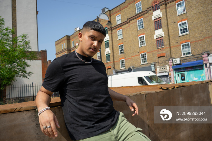 Man wearing back tshirt leaning on wall