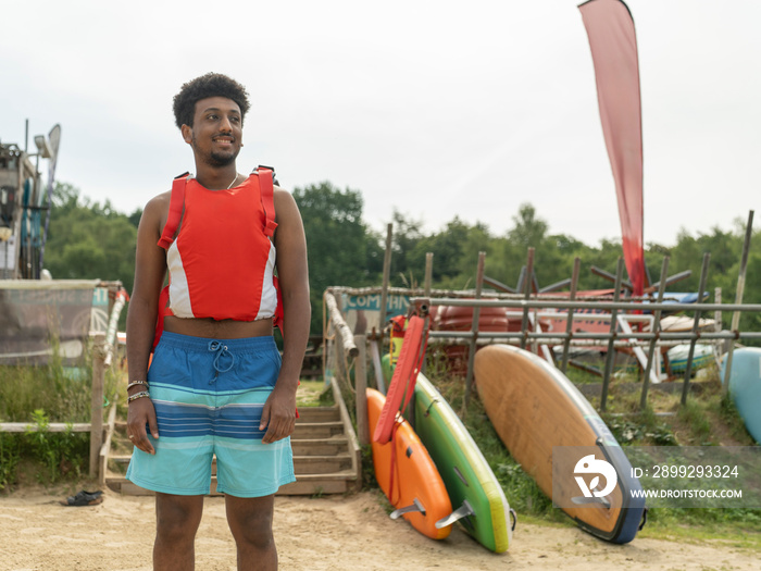 Portrait of young man standing on beach before paddleboarding