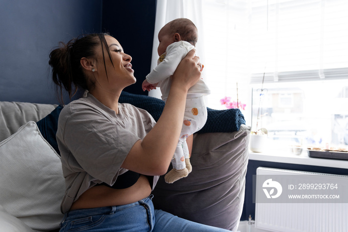 Smiling mother carrying newborn baby girl at home