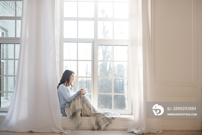 Dark-haired young woman looking out the window