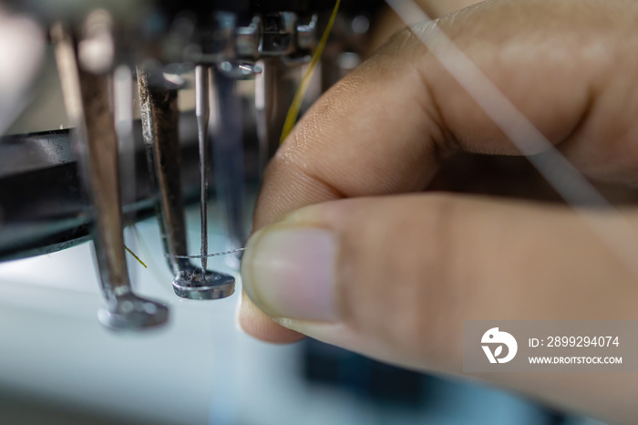 Worker hand putting thread on embroidery needle in Textile Industry at Garment Manufacturers, Embroidery needle, Needle with thread (selective focus and soft focus)