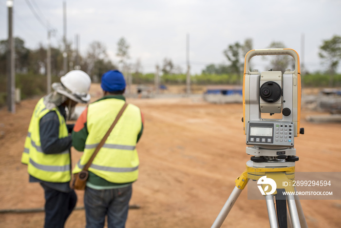 Surveyor equipment tacheometer or theodolite outdoors at construction site and construction worker in safety uniform