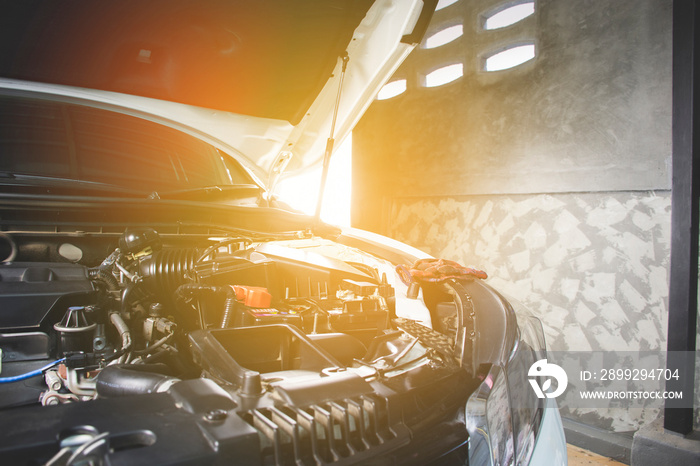 Car open hood in vehicle repair shop for maintenance service by mechanic,sunlight on background.