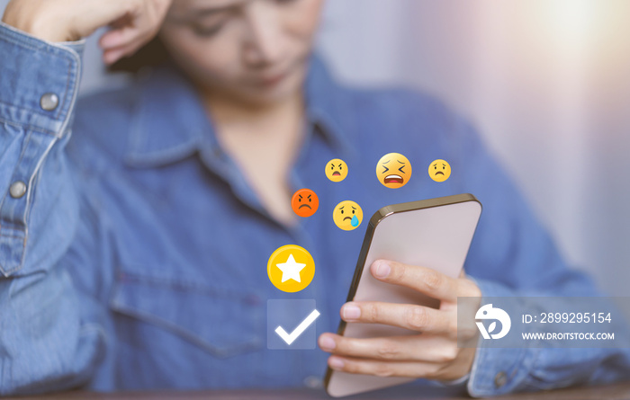 Customer service evaluation concept. Woman using a smartphone gives a 1-star rating by choosing dissatisfied, disappointed, and angry emoticons on the virtual screen, bad experiences, and bad reviews.