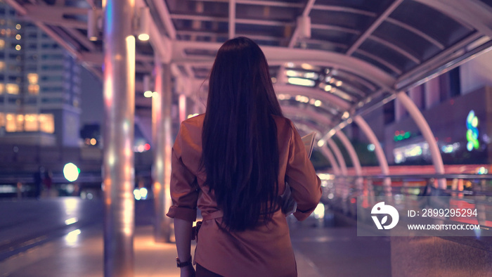 Young asian woman walking in the night city streets