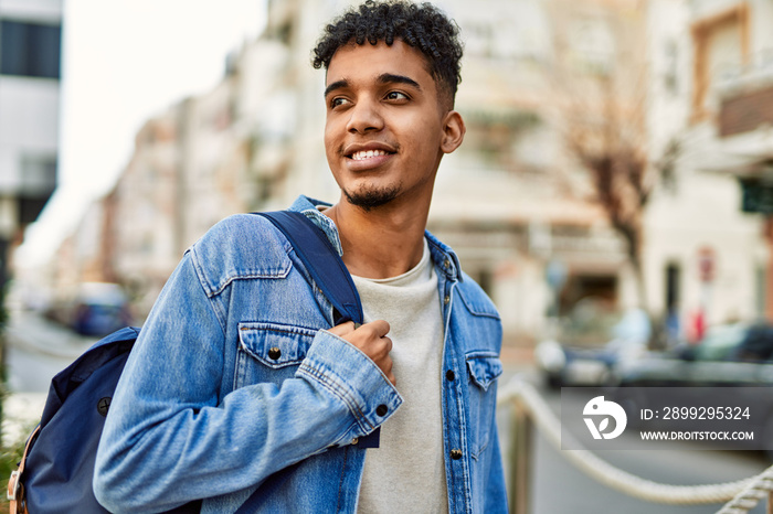 Hispanic young man smiling at the street