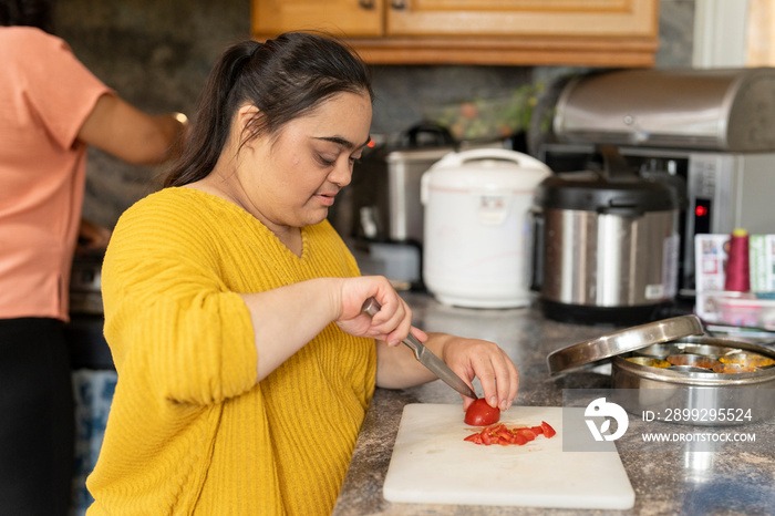 Woman with down syndrome preparing food with mother in kitchen