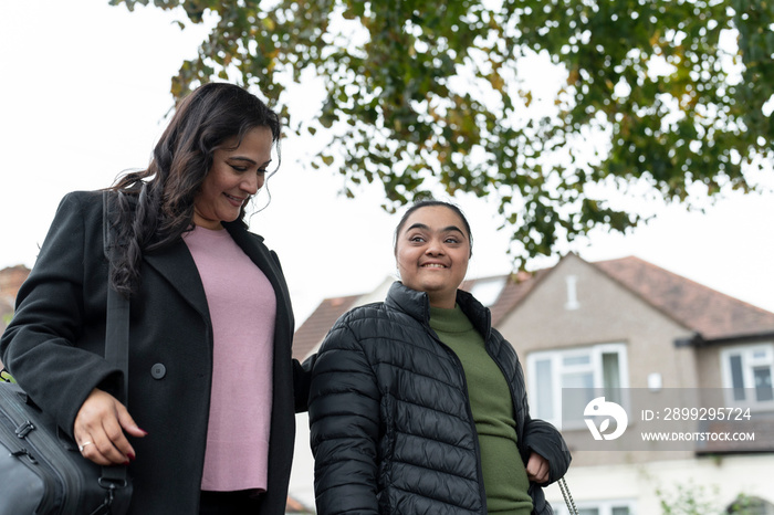 Mother walking with down syndrome daughter in residential district