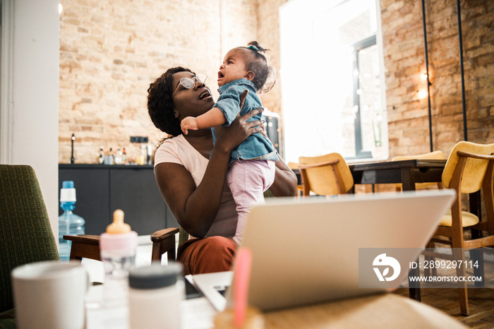 Loving mother holding crying baby girl at home