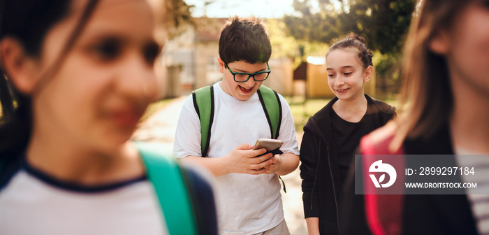 Boy standing with friends using smart phone at schoolyard