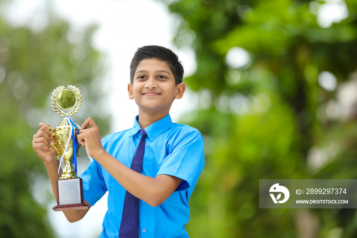 Clever schoolboy raising his trophy as a winner in school competition.