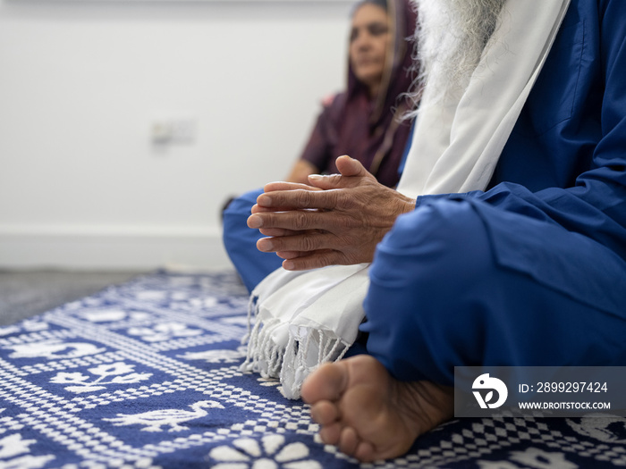 Senior couple in traditional clothing praying at home