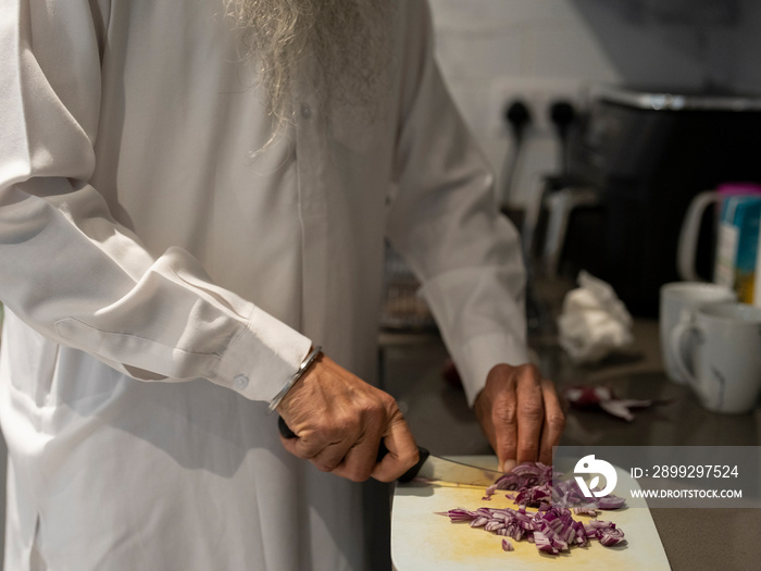 Senior man chopping onion in kitchen