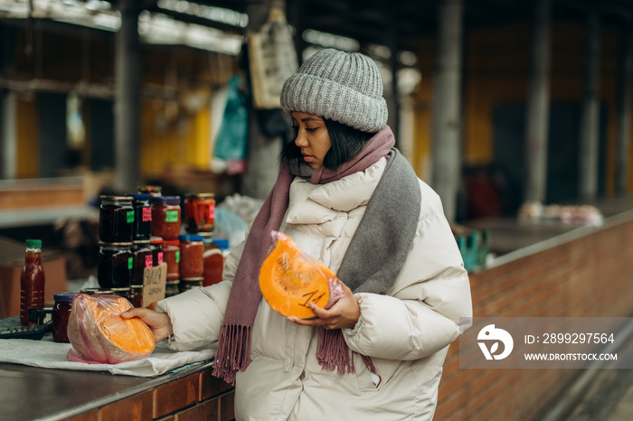 An African American woman is shopping at a local street market. He also chooses fresh fragrant fruits.