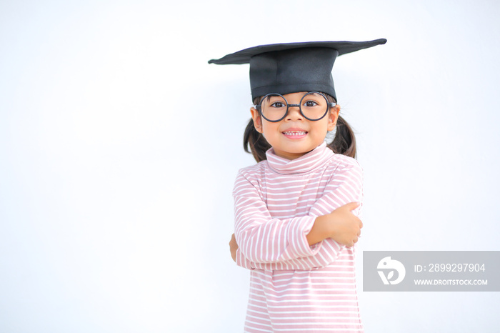 A little girl asia looks happy while celebrating his graduation and holding a diploma and graduation cap  which increases the development and enhances outside the classroom learning skills concept.