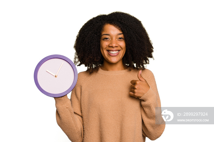 Young African American holding a clock isolated smiling and raising thumb up