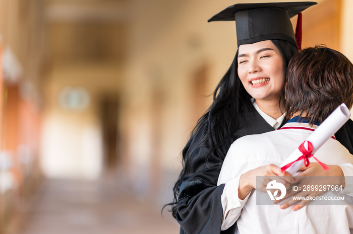 Happy student hugging her friend and celebrating her graduation