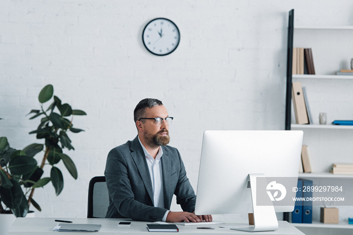 handsome businessman in formal wear and glasses using computer