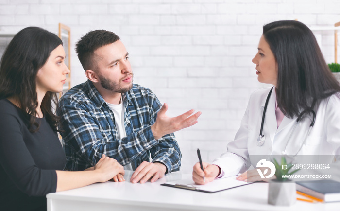Young childless couple consulting with doctor at clinic