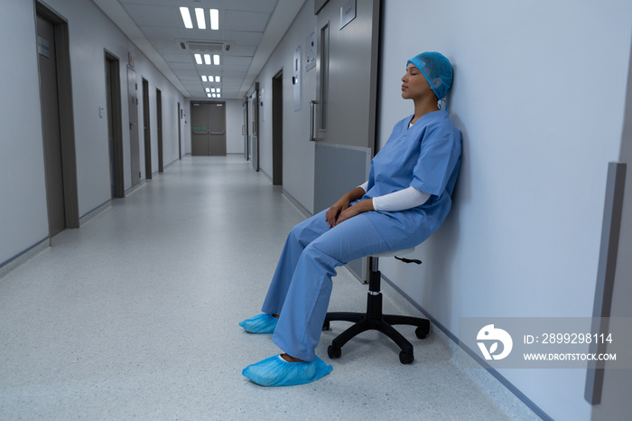 Tensed female surgeon sitting on stool in the corridor