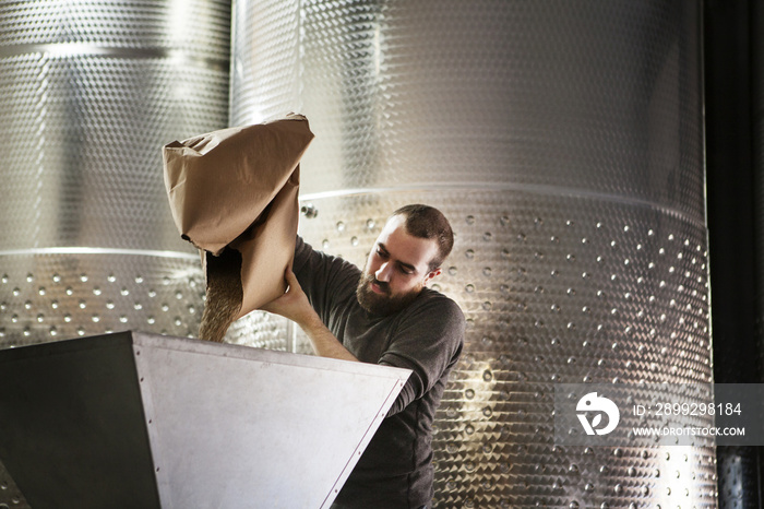 Man pouring barley in machinery at distillery