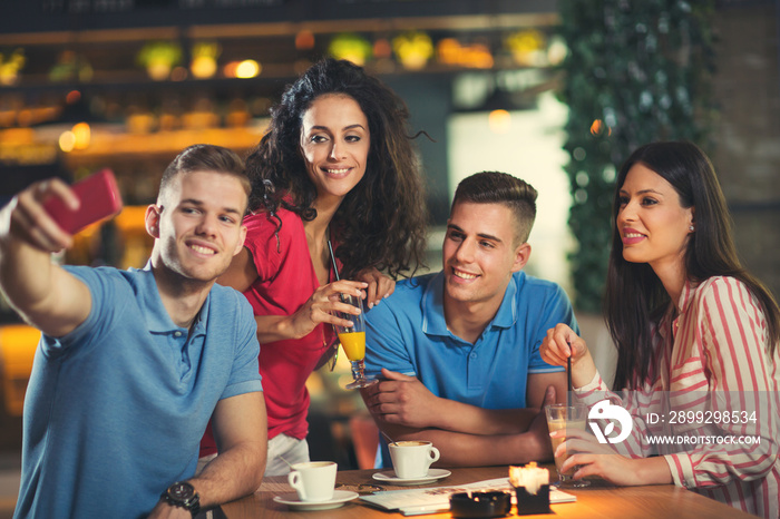 Group of young people meeting in a cafe make selfie photo.