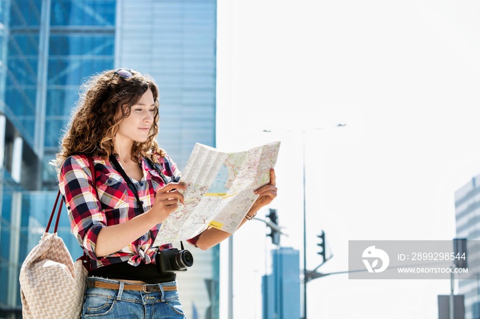 Portrait of young attractive woman looking on map in the middle of the city