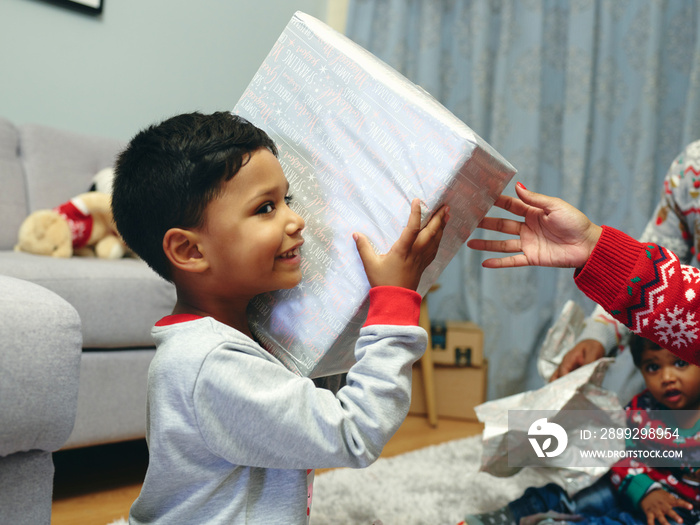 Boy opening Christmas presents with family