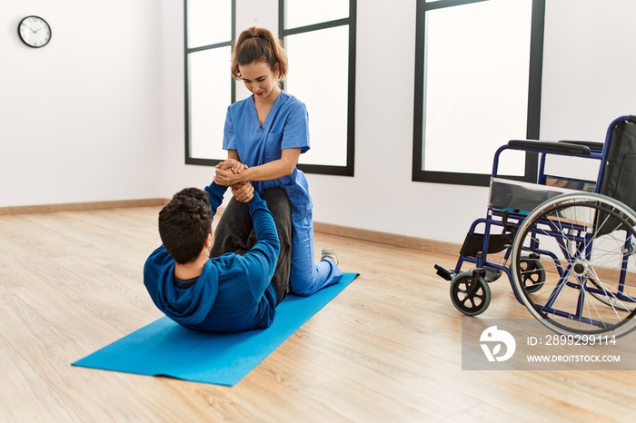 Young disabled man making mobility exercise at the clinic.