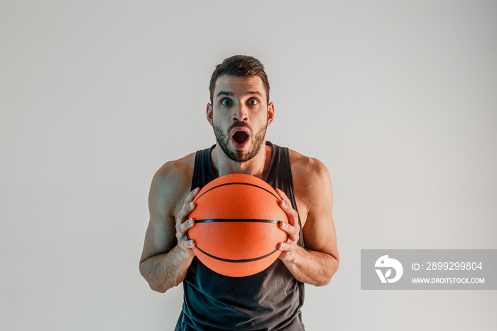 Surprised sportsman hold basketball ball in studio