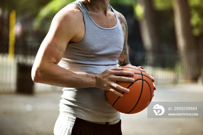 Midsection of man holding basketball in court