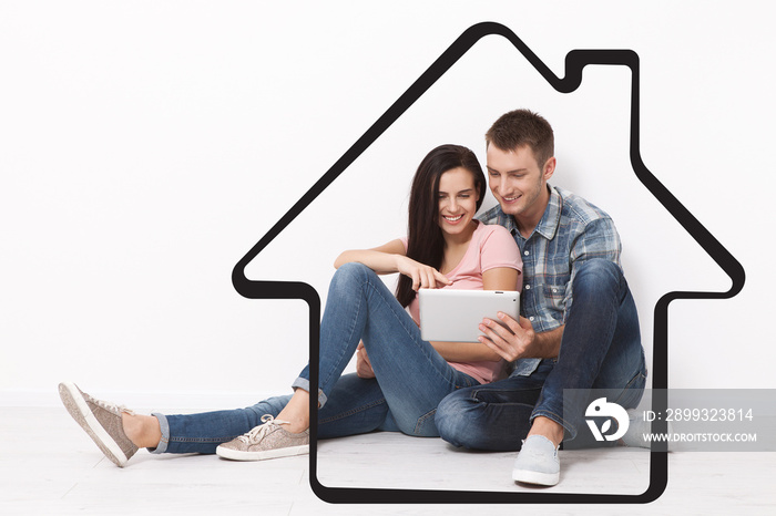 Happy young couple sitting on the floor using a tablet for shopping and entertainment. Layout.