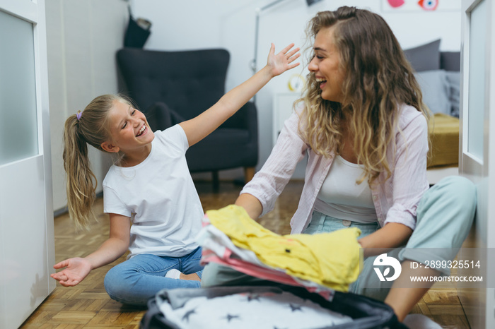 mother and daughter packing suitcase for vacation