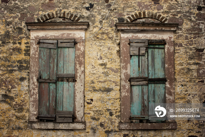 Close up view of old, rusty, closed wooden shutters and stone wa